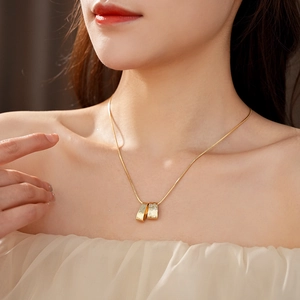 Macro detail of gold necklace with zircon stones and textured double ring pendant