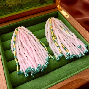 Close-up of pink beaded fringe earrings with green accents on green velvet background