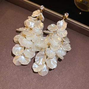 Detailed view of layered white petal tassel earrings with gold accents and rhinestones
