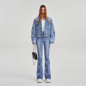Détail d'un ensemble en jean bleu délavé avec veste courte et jean évasé sur modèle