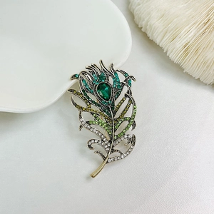 Detailed macro view of vintage peacock feather brooch with colorful zircon and green stone