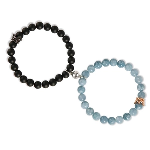 Detail of magnetic couple bracelets with black and sky blue agate beads and crown charms