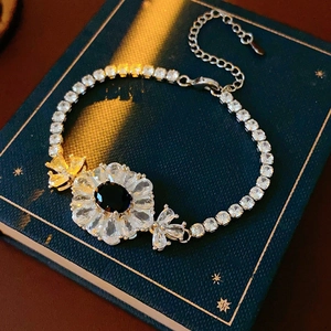 Detail des funkelnden Blumenarmband mit schwarzem Ovalstein auf einem Vintage-Buch