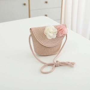 Close-up of pink woven straw bag with delicate floral decorations for girls