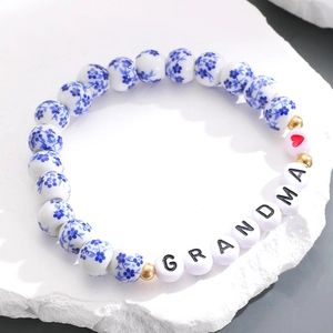 Dettaglio di perline in ceramica blu e bianca con lettere GRANDMA su bracciale elastico