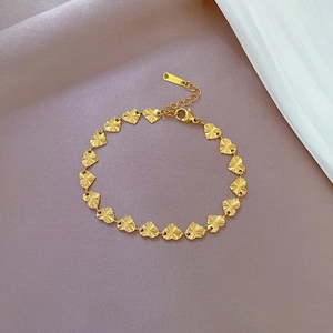 Detail of gold heart chain bracelet made of stainless steel on purple background