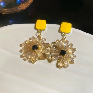 Detailed macro view of yellow square stud earrings with crystal daisy flower pendants