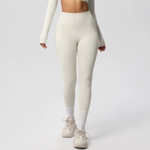Detail view of high-waisted beige yoga leggings featuring practical side pockets and matte fabric