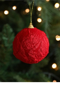 Detailed view of red textured Christmas ornament ball with gold string on tree