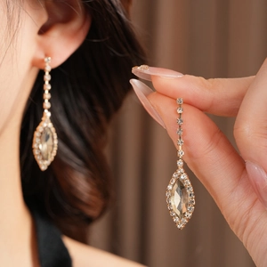 Detail of elegant gold-tone drop earrings with champagne marquise stones and tassels
