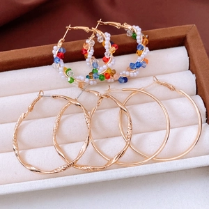 Close-up of golden hoop earrings with pearls and colorful faceted beads in a jewelry box