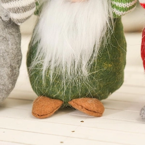 Macro view of handmade Christmas gnome doll with fluffy white beard and green felt body
