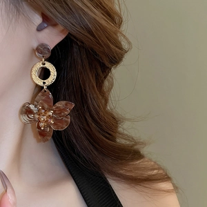 Close-up of vintage resin flower earrings with gold hammered ring on model ear