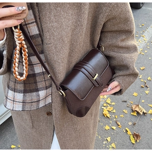 Detail of vintage brown crossbody bag with mixed textures and colorful braided cord strap