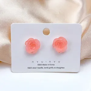 Detail shot of pink rose earrings with S925 silver needles on premium silk background