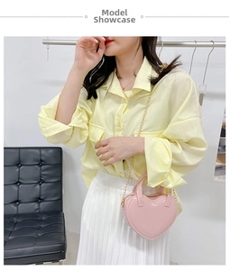 Pink heart-shaped mini jelly bag with glossy finish and gold chain strap on model