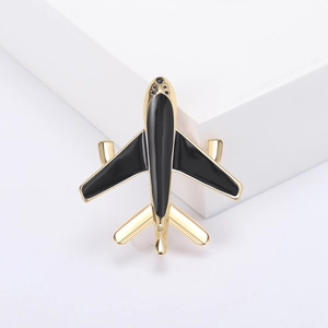 Detailed close-up of a gold-plated airplane brooch with black enamel and crystal rhinestones