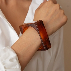 Close-up of a square amber resin bracelet with marbled pattern on a model's wrist