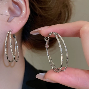 Detail view and model wearing silver double-layered bamboo texture hoop earrings
