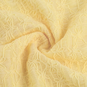 Detailed macro shot of premium yellow lace fabric showing intricate floral weaving patterns