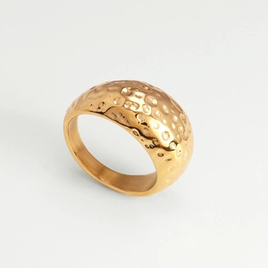 Detail view of the wide golden hammered texture ring with a unique wavy metallic finish