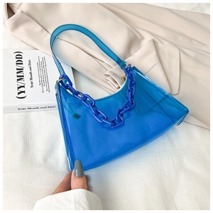 Detail of blue transparent jelly shoulder bag with plastic chain on beige blazer jacket