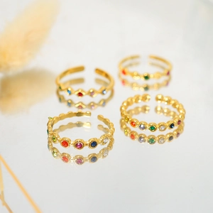 Macro detail of four gold adjustable rings with colorful zircon stones on a mirror surface