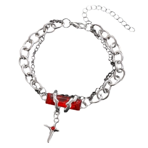 Close-up of gothic silver chain bracelet with faceted red gemstone and small cross pendant