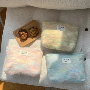 Detailed close-up of colorful plush knit makeup bags with brand tags and soft fuzzy textures
