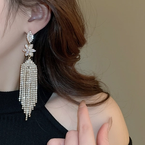 Close-up of elegant gold tassel flower earrings with rhinestones on a female model