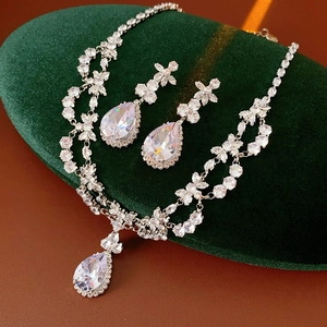 Macro view of crystal flower necklace and teardrop earrings on green velvet pad