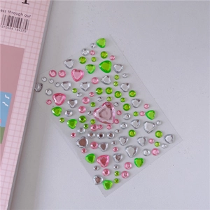 Macro shot of 3D acrylic heart and round diamond stickers in pink, green and silver