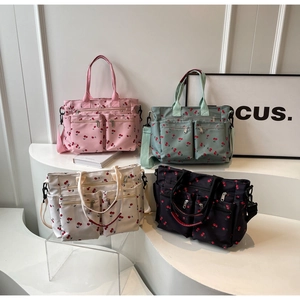Detail view of multi-color cherry print tote bags with multiple zipper pockets