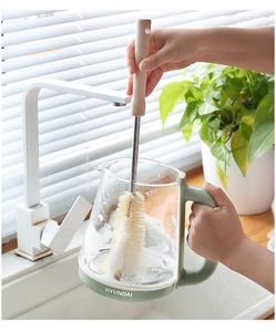 Détail d'une brosse à manche long en bois nettoyant l'intérieur d'une bouilloire en verre