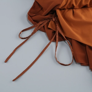 Close-up of caramel halter dress featuring ruffle details and ruched drawstring texture