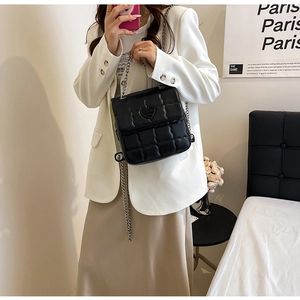 Detail of black heart-quilted leather square bag with dual silver chain shoulder straps