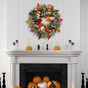 Close-up of fall wreath with white pumpkins and maple leaves on a white fireplace