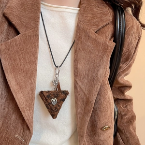 Detail of plush brown leopard triangle pendant on black cord worn over a corduroy blazer