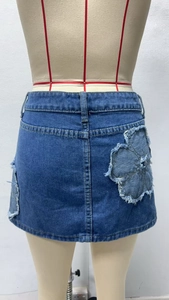 Detail of floral patchwork and frayed hem on a blue denim mini skirt for women