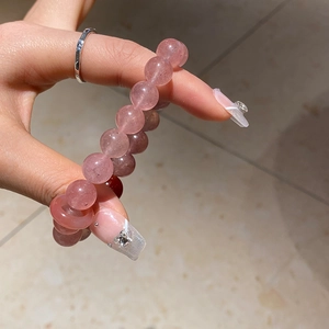 Close-up of pink strawberry quartz and pearl beaded bracelet on hand with manicure