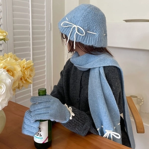 Detailed view of light blue knit set featuring a soft scarf, beanie with bow, and warm gloves