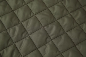 Vue macro du tissu matelassé à losanges vert olive avec finition satinée de qualité