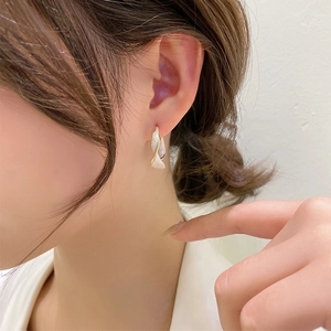 Close-up of elegant cream twisted hoop earrings with golden edges on model ear