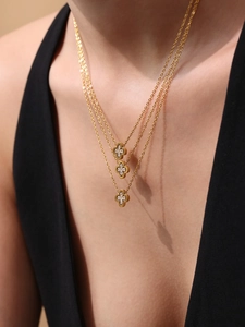 Detailed view of triple-layered gold clover necklace with sparkling cubic zirconia on model
