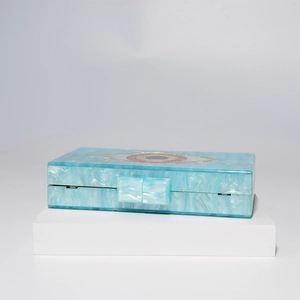 Teal marble acrylic box clutch with Evil Eye inlay on white pedestal for wedding party