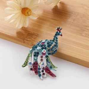 Detailed view of peacock brooch with colorful rhinestones on a natural wooden background