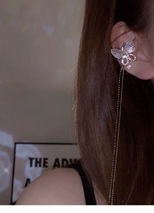 Detail view of sparkling butterfly tassel ear cuff with rhinestones on a female model