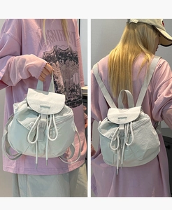 Detail of white nylon mini backpack featuring drawstring closure and front pockets