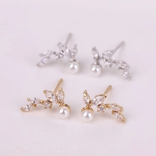 Detail of silver and gold leaf earrings with small zircons and pendant pearls