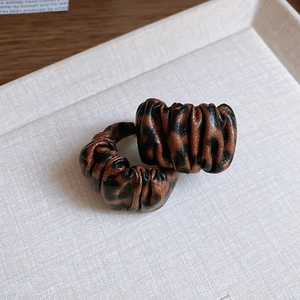 Close-up of leopard print resin earrings with pleated leather texture on a display tray